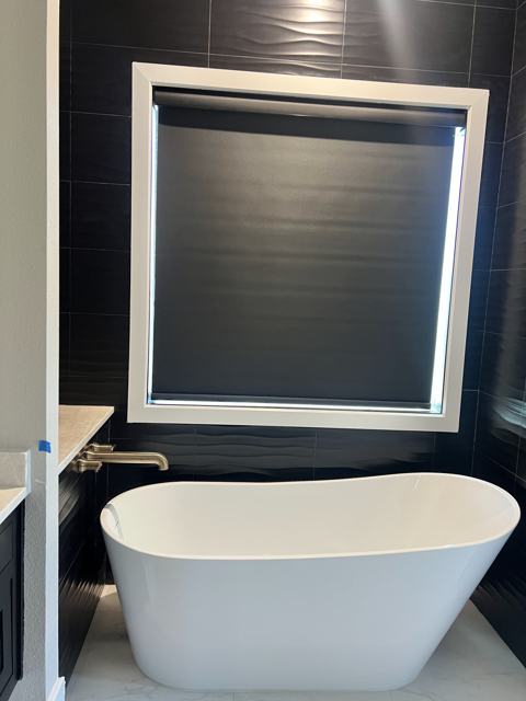 Black roller shade above a soaking tub